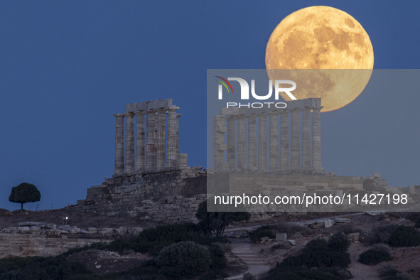 The Full Buck Moon rises behind the ancient Greek Temple of Poseidon on Cape Sounion in Greece on July 20, 2024 