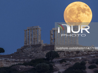 The Full Buck Moon rises behind the ancient Greek Temple of Poseidon on Cape Sounion in Greece on July 20, 2024 (