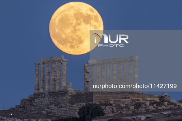 The Full Buck Moon rises behind the ancient Greek Temple of Poseidon on Cape Sounion in Greece on July 20, 2024 