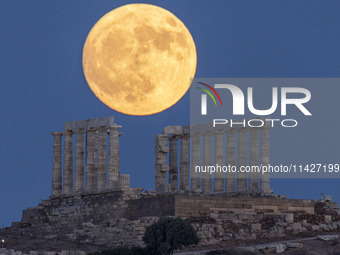 The Full Buck Moon rises behind the ancient Greek Temple of Poseidon on Cape Sounion in Greece on July 20, 2024 (