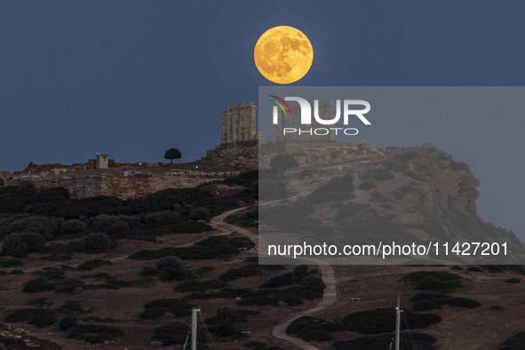 The Full Buck Moon rises behind the ancient Greek Temple of Poseidon on Cape Sounion in Greece on July 20, 2024 