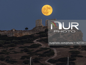 The Full Buck Moon rises behind the ancient Greek Temple of Poseidon on Cape Sounion in Greece on July 20, 2024 (