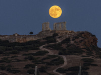 The Full Buck Moon rises behind the ancient Greek Temple of Poseidon on Cape Sounion in Greece on July 20, 2024 (