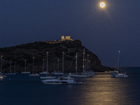 The Full Buck Moon rises behind the ancient Greek Temple of Poseidon on Cape Sounion in Greece with ships in the sea, on July 20, 2024 (