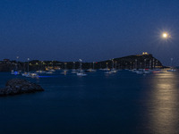 The Full Buck Moon rises behind the ancient Greek Temple of Poseidon on Cape Sounion in Greece with ships in the sea, on July 20, 2024 (