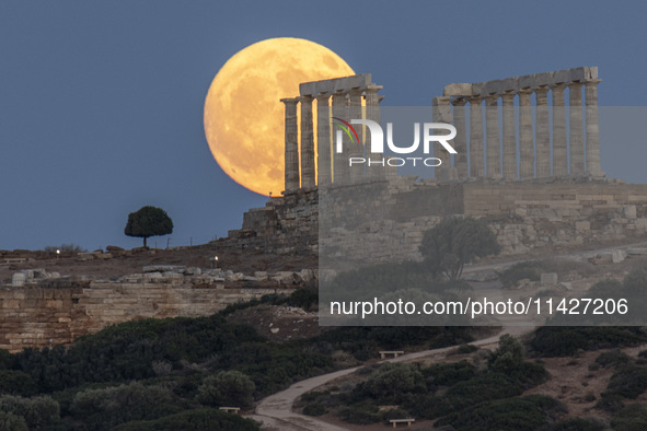 The Full Buck Moon rises behind the ancient Greek Temple of Poseidon on Cape Sounion in Greece on July 20, 2024 