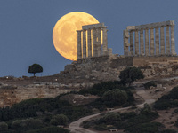 The Full Buck Moon rises behind the ancient Greek Temple of Poseidon on Cape Sounion in Greece on July 20, 2024 (