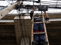 A municipal worker is standing on a bamboo ladder to perform maintenance on a mess of electrical wires in Bangkok, Thailand, on July 22, 202...