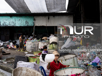 Burmese workers are sorting rotting food waste, fabric, and recyclable plastic by hand at a sorting facility in Bangkok, Thailand, on July 2...