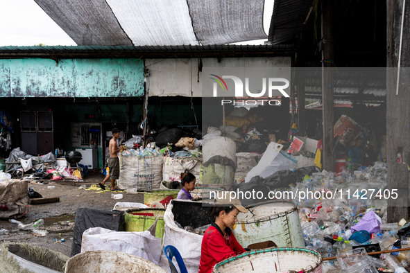 Burmese workers are sorting rotting food waste, fabric, and recyclable plastic by hand at a sorting facility in Bangkok, Thailand, on July 2...