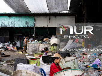 Burmese workers are sorting rotting food waste, fabric, and recyclable plastic by hand at a sorting facility in Bangkok, Thailand, on July 2...