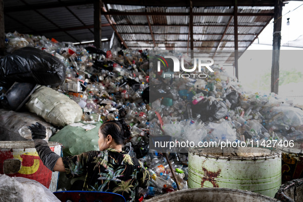 Burmese workers are sorting rotting food waste, fabric, and recyclable plastic by hand at a sorting facility in Bangkok, Thailand, on July 2...