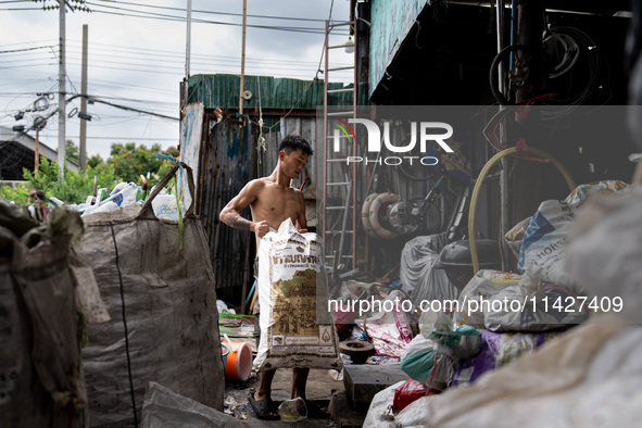 A worker is carrying a bag of waste for weighing at a sorting facility in Bangkok, Thailand, on July 22, 2024 