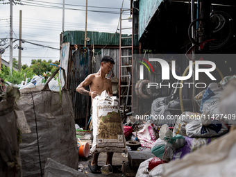 A worker is carrying a bag of waste for weighing at a sorting facility in Bangkok, Thailand, on July 22, 2024 (