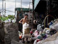 A worker is carrying a bag of waste for weighing at a sorting facility in Bangkok, Thailand, on July 22, 2024 (