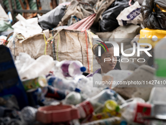 Burmese workers are sorting rotting food waste, fabric, and recyclable plastic by hand at a sorting facility in Bangkok, Thailand, on July 2...