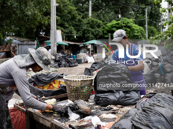 Burmese workers are sorting rotting food waste, fabric, and recyclable plastic by hand at a sorting facility in Bangkok, Thailand, on July 2...