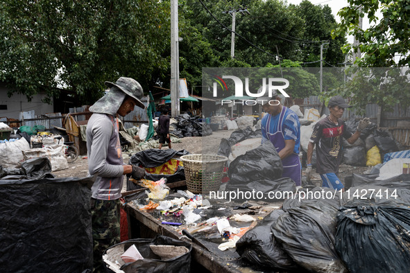 Burmese workers are sorting rotting food waste, fabric, and recyclable plastic by hand at a sorting facility in Bangkok, Thailand, on July 2...