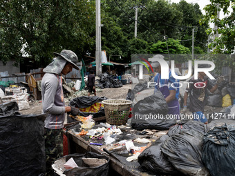 Burmese workers are sorting rotting food waste, fabric, and recyclable plastic by hand at a sorting facility in Bangkok, Thailand, on July 2...