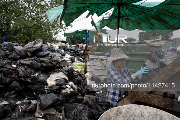 Burmese workers are sorting rotting food waste, fabric, and recyclable plastic by hand at a sorting facility in Bangkok, Thailand, on July 2...