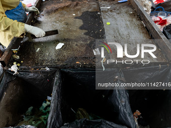 Burmese workers are sorting rotting food waste, fabric, and recyclable plastic by hand at a sorting facility in Bangkok, Thailand, on July 2...