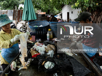 Burmese workers are sorting rotting food waste, fabric, and recyclable plastic by hand at a sorting facility in Bangkok, Thailand, on July 2...