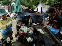 Burmese workers are sorting rotting food waste, fabric, and recyclable plastic by hand at a sorting facility in Bangkok, Thailand, on July 2...