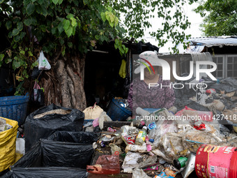 Burmese workers are sorting rotting food waste, fabric, and recyclable plastic by hand at a sorting facility in Bangkok, Thailand, on July 2...