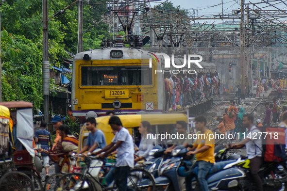 People are crossing a railway track as a train is leaving the station in Kolkata, India, on July 22, 2024. It is expected that the railway i...