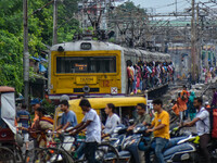 People are crossing a railway track as a train is leaving the station in Kolkata, India, on July 22, 2024. It is expected that the railway i...