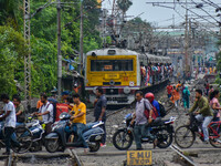 People are crossing a railway track as a train is leaving the station in Kolkata, India, on July 22, 2024. It is expected that the railway i...