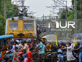 People are crossing a railway track as a train is leaving the station in Kolkata, India, on July 22, 2024. It is expected that the railway i...