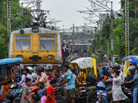 People are crossing a railway track as a train is leaving the station in Kolkata, India, on July 22, 2024. It is expected that the railway i...