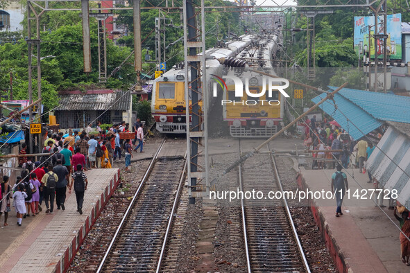 People are crossing a railway track as a train is leaving the station in Kolkata, India, on July 22, 2024. It is expected that the railway i...