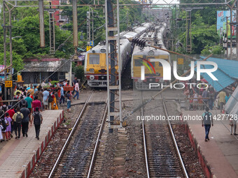 People are crossing a railway track as a train is leaving the station in Kolkata, India, on July 22, 2024. It is expected that the railway i...