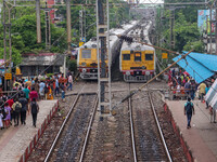 People are crossing a railway track as a train is leaving the station in Kolkata, India, on July 22, 2024. It is expected that the railway i...