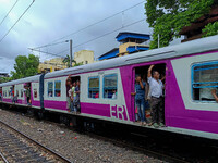 People are hanging from a train door as they are traveling in a local train in Kolkata, India, on July 22, 2024. It is expected that the rai...