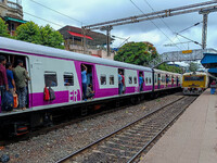 People are hanging from a train door as they are traveling in a local train in Kolkata, India, on July 22, 2024. It is expected that the rai...