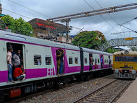 People are hanging from a train door as they are traveling in a local train in Kolkata, India, on July 22, 2024. It is expected that the rai...