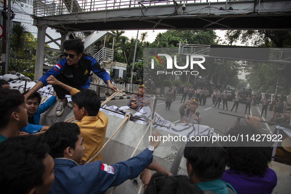 Students from various universities are trying to break through a barrier as they stage a demonstration to commemorate 10 years of Jokowi's g...