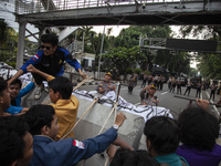 Students from various universities are trying to break through a barrier as they stage a demonstration to commemorate 10 years of Jokowi's g...