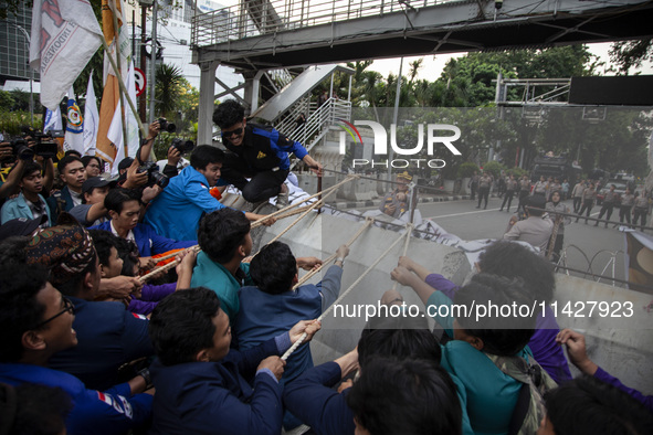 Students from various universities are trying to break through a barrier as they stage a demonstration to commemorate 10 years of Jokowi's g...