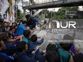 Students from various universities are trying to break through a barrier as they stage a demonstration to commemorate 10 years of Jokowi's g...