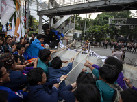 Students from various universities are trying to break through a barrier as they stage a demonstration to commemorate 10 years of Jokowi's g...