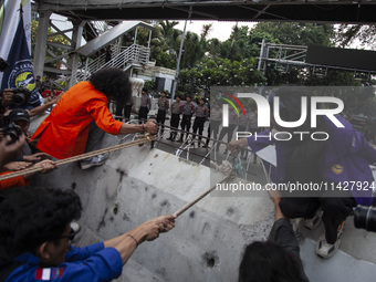 Students from various universities are trying to break through a barrier as they stage a demonstration to commemorate 10 years of Jokowi's g...