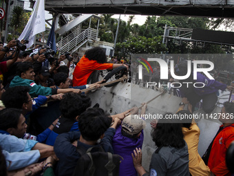 Students from various universities are trying to break through a barrier as they stage a demonstration to commemorate 10 years of Jokowi's g...