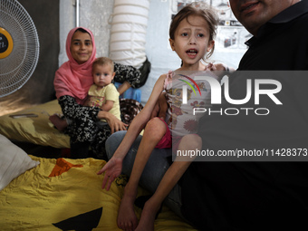 A doctor is holding Jana Ayad, a malnourished Palestinian girl, as she is receiving treatment at the International Medical Corps field hospi...