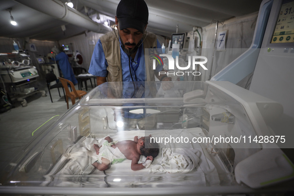 A doctor is checking a baby lying in an incubator at the newborns' intensive care unit at the International Medical Corps field hospital, am...