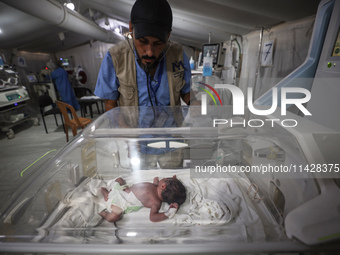 A doctor is checking a baby lying in an incubator at the newborns' intensive care unit at the International Medical Corps field hospital, am...