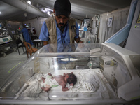 A doctor is checking a baby lying in an incubator at the newborns' intensive care unit at the International Medical Corps field hospital, am...